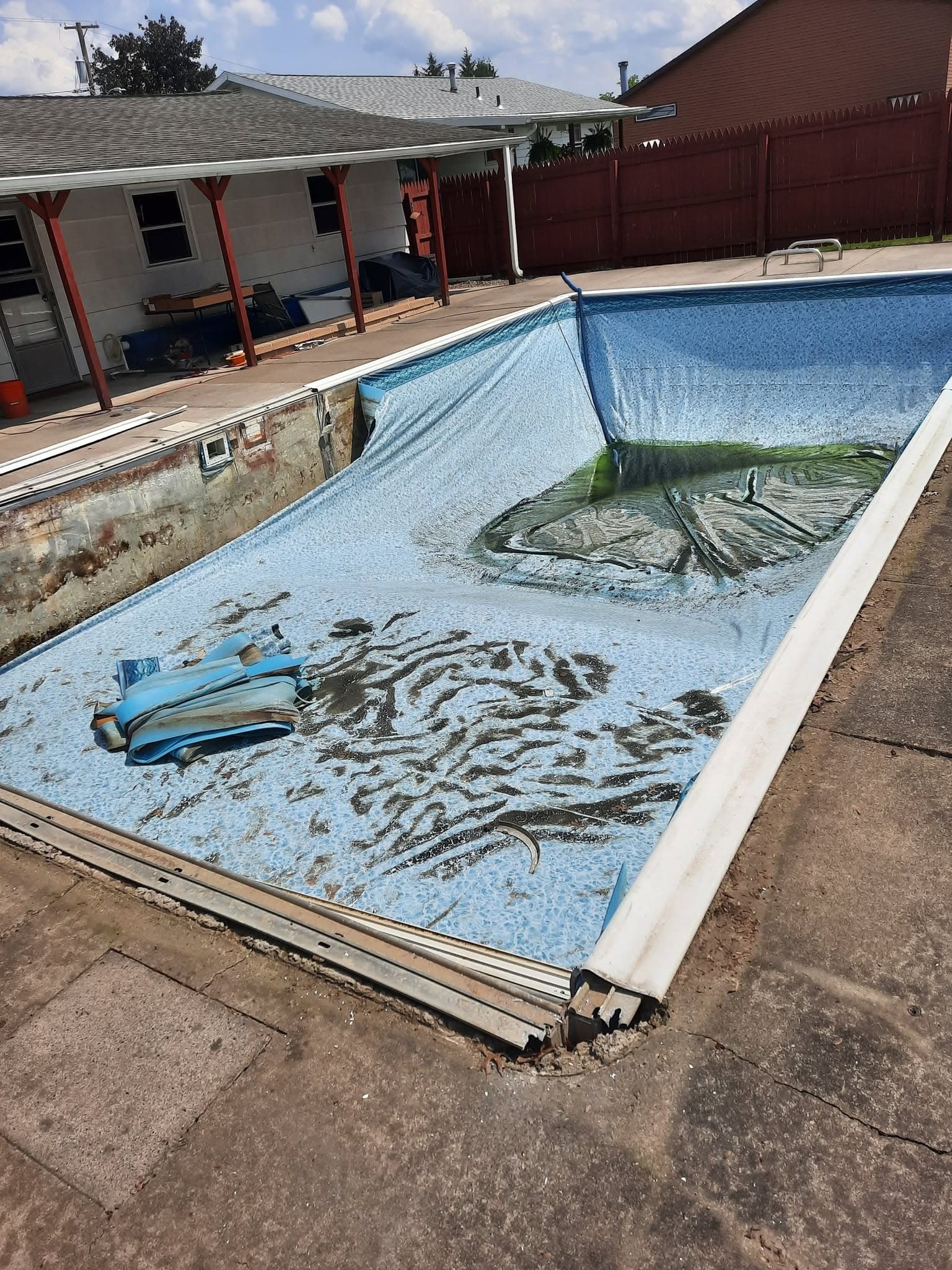 Pool before: torn wrinkled liner and rusted walls